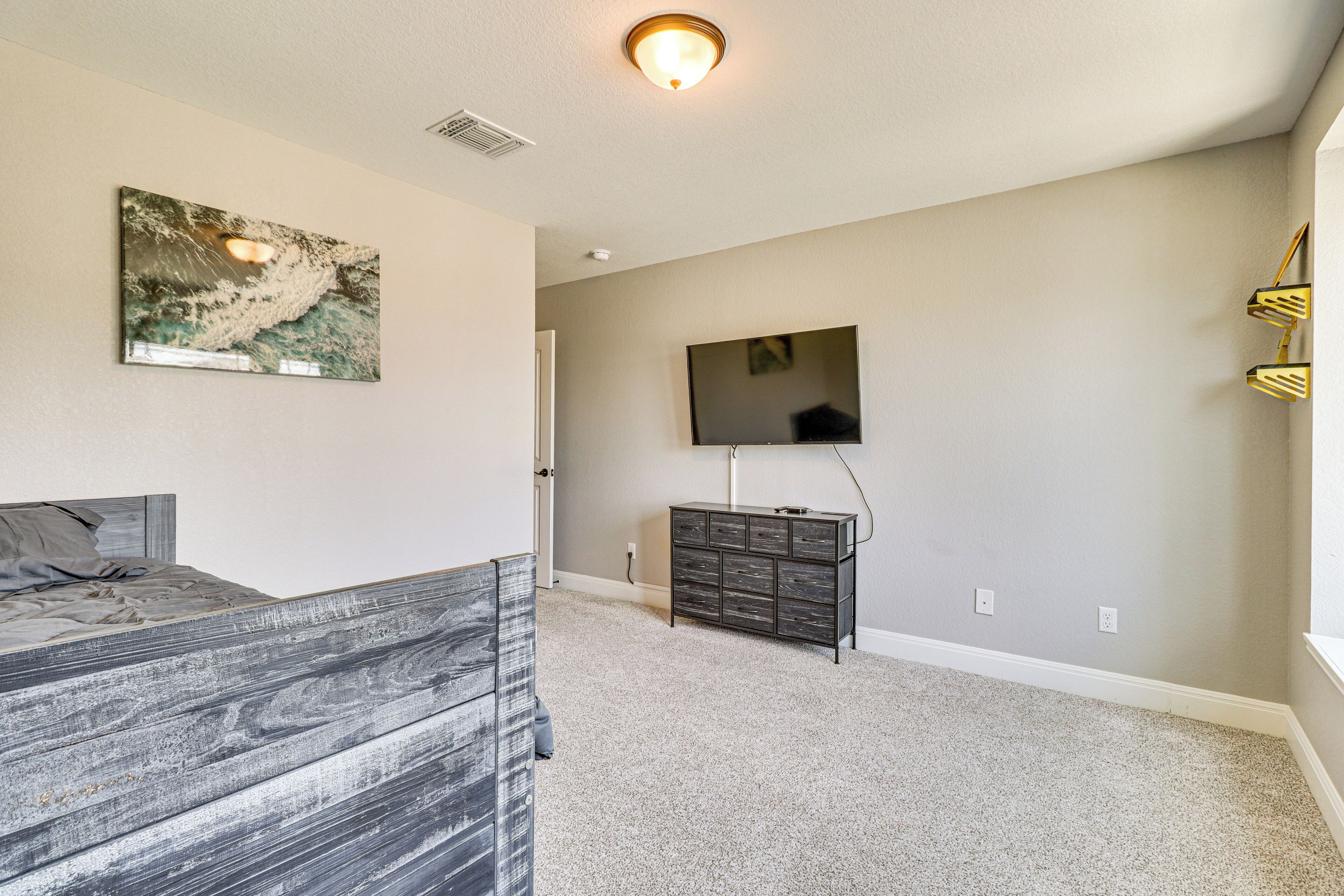 A bedroom with a bed, a dresser, a television mounted on the wall, and a carpeted floor.