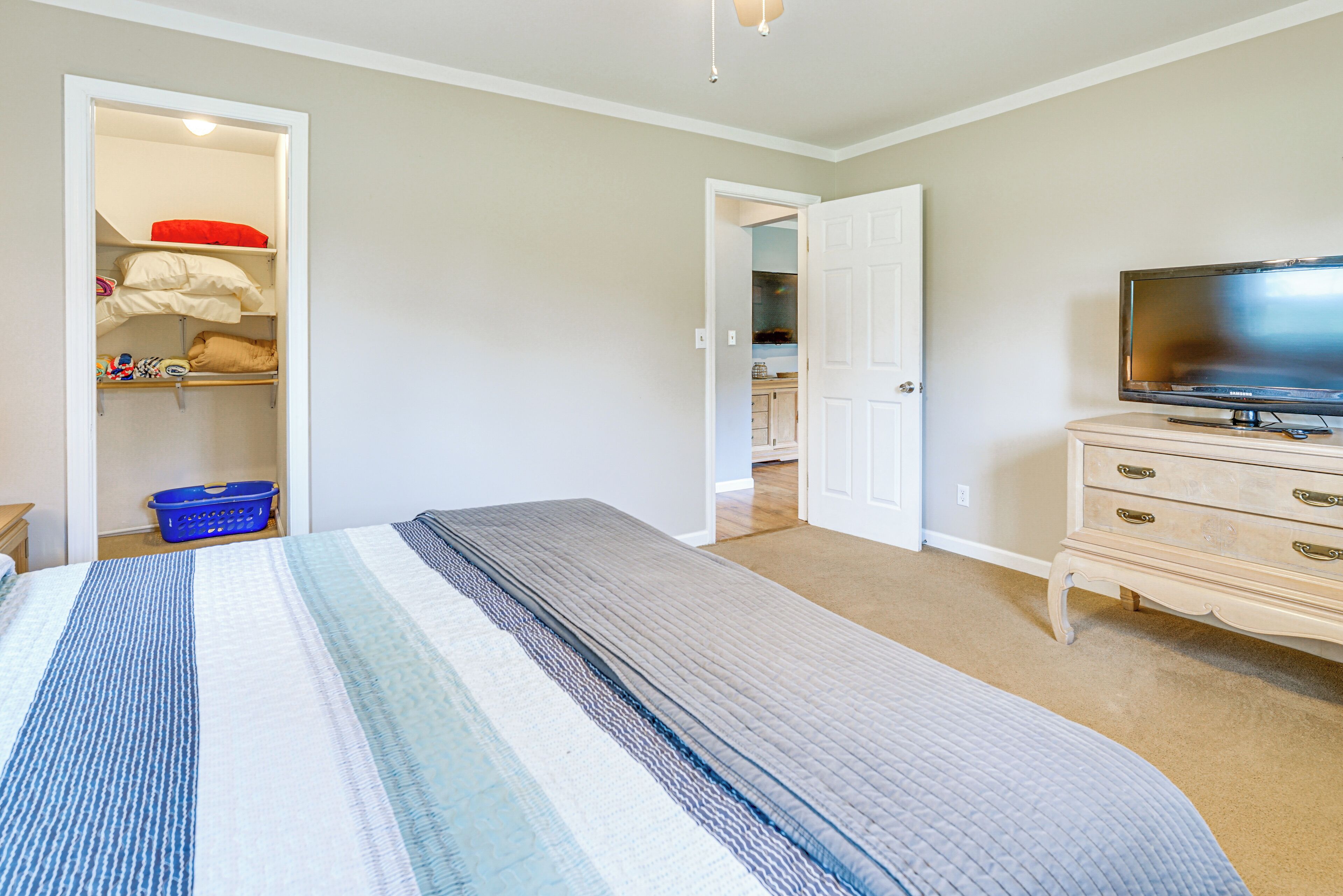 A bedroom with a bed, a dresser, a television, and a closet.