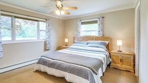 A bedroom with a bed, two bedside tables, a ceiling fan, and windows with curtains. - 1 Block to Lake Huron: Pet-friendly Apt w/ Kayaks (Lexington)