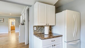 A kitchen with white cabinets, a granite countertop, and a white refrigerator. - 1 Block to Lake Huron: Pet-friendly Apt w/ Kayaks (Lexington)