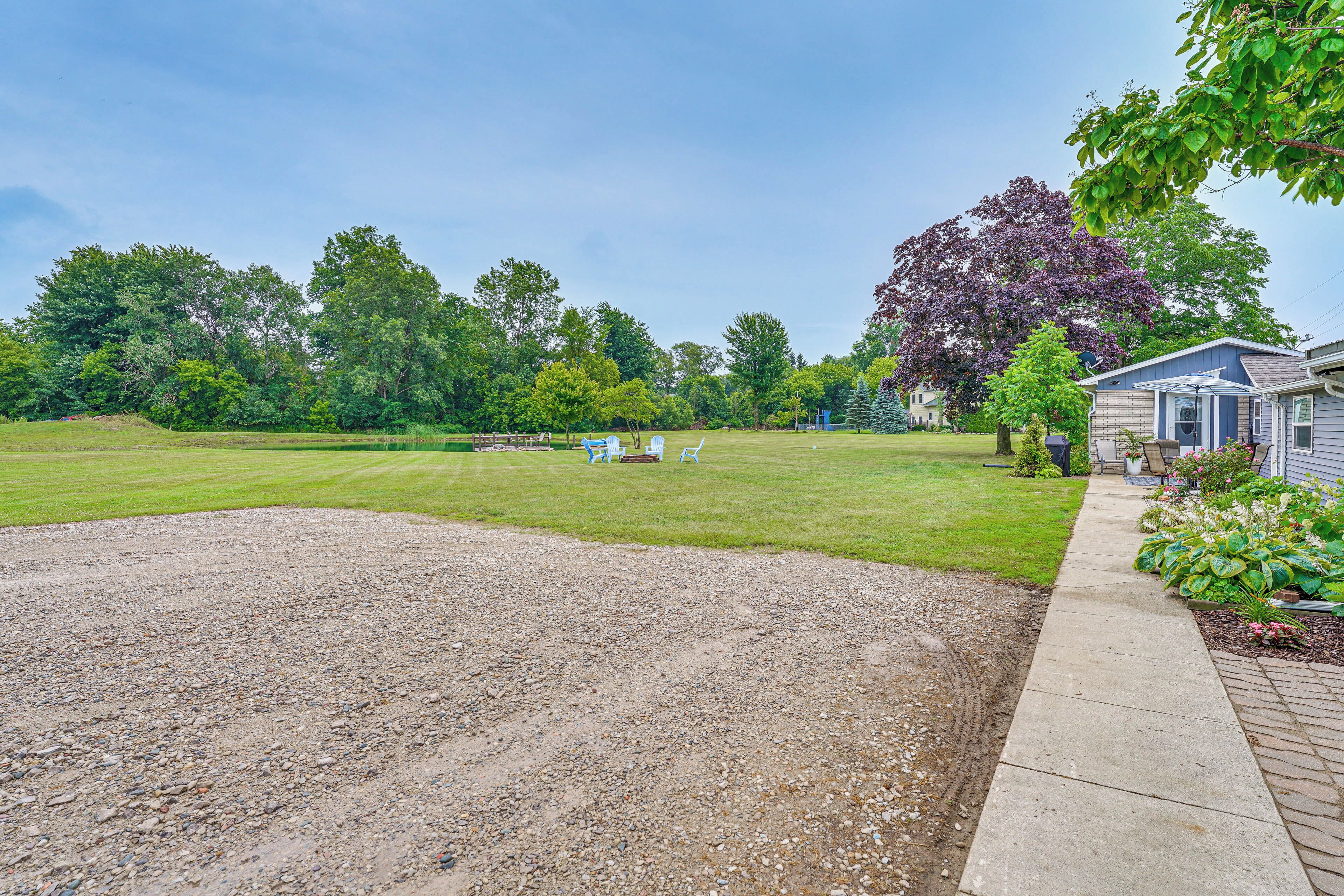 A residential property with a large lawn, a gravel driveway, and a house with a blue exterior.