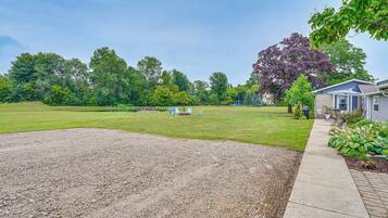 A residential property with a large lawn, a gravel driveway, and a house with a blue exterior.