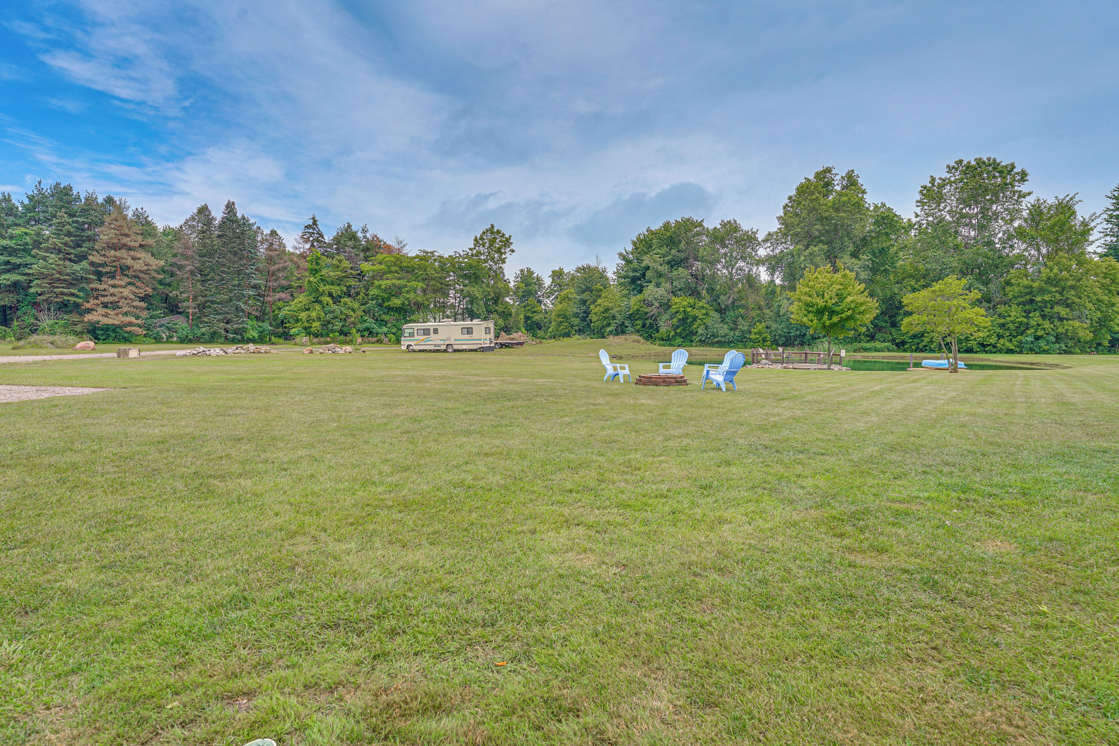A grassy field with a caravan and blue chairs.