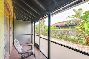 Un balcón cubierto con vistas a un jardín y un edificio.