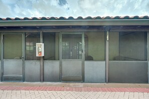 A building with large glass doors and windows, a tiled roof, and a brick-paved entrance.