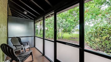 A covered outdoor area with a bench and large windows overlooking a garden.