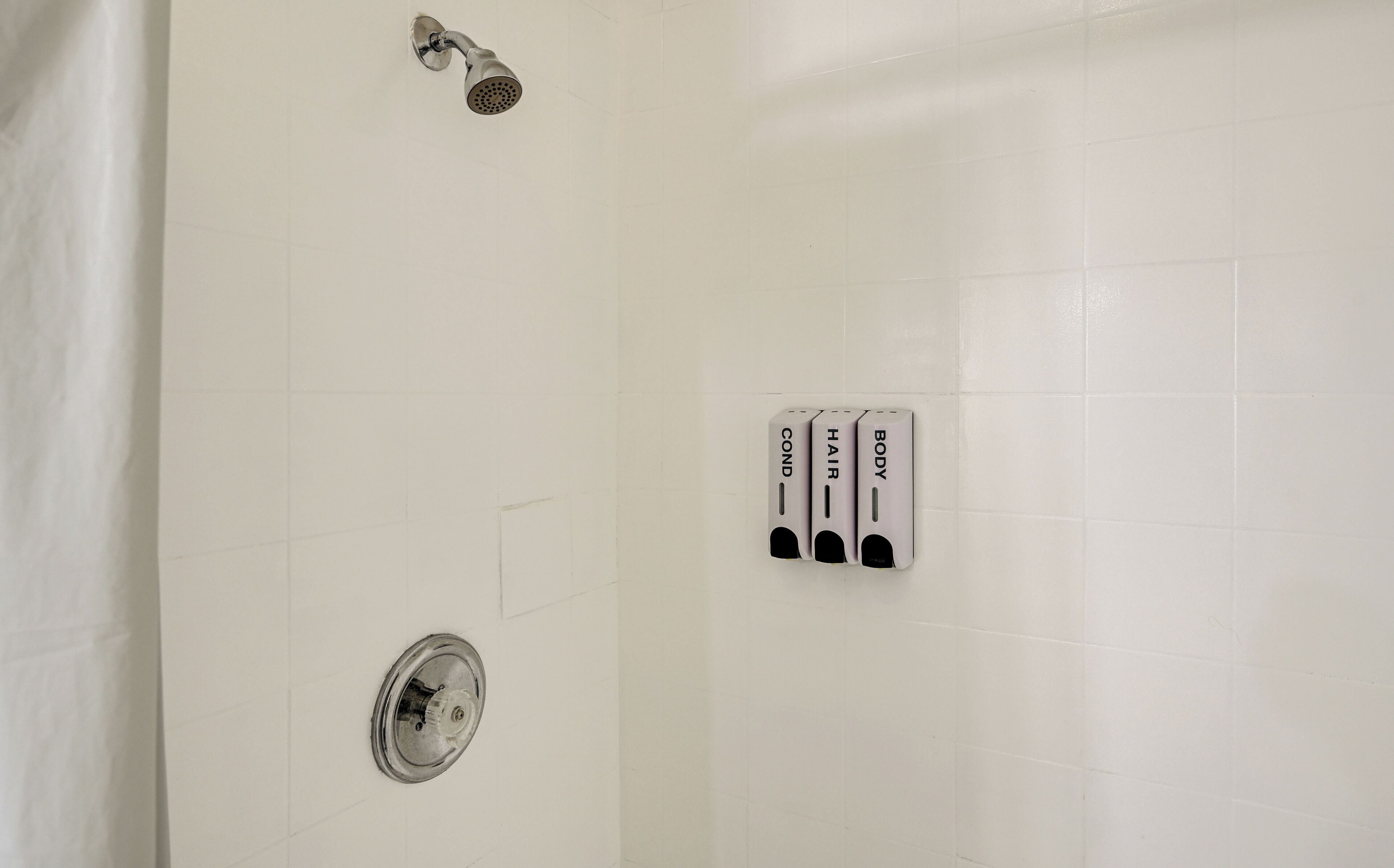 A bathroom with a shower, a toilet, and a hand dryer.