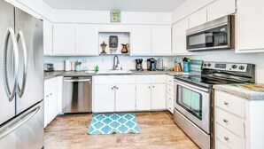 Une cuisine moderne avec des meubles blancs, des appareils en acier inoxydable et un plancher en bois.