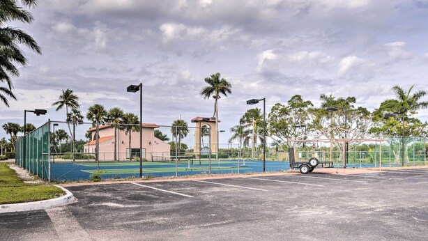 A sports court with a fence, palm trees, and a building with a clock tower. - Resort on Marina: Everglades Escape on Heated Pool (Naples)
