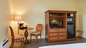 A hotel room with a wooden cabinet containing a television, microwave, and a small refrigerator. There is a dining table with a lamp and a chair. - Resort on Marina: Everglades Escape on Heated Pool (Naples)