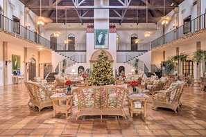 A spacious lobby with a central Christmas tree, multiple seating areas, and a staircase connecting floors. - Resort on Marina: Everglades Escape on Heated Pool (Naples)