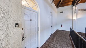 A hallway with a white door, a patterned carpet, and a wooden ceiling. - Resort on Marina: Everglades Escape on Heated Pool (Naples)
