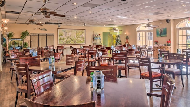 A spacious restaurant with multiple tables and chairs, ceiling fans, and large windows. - Poolside Paradise w/ Dock in Everglades! (Naples)
