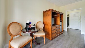 A room with a wooden cabinet, two upholstered chairs, a round table with a coffee maker, and a door in the background. - Direct Access to 10,000 Islands: Everglades Escape (Naples)