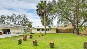 Propiedad residencial con césped cuidado, varios árboles y una casa con garaje y cochera.