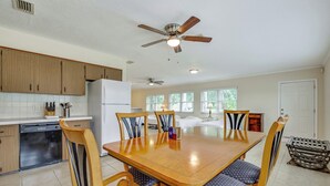 Una cocina amplia con armarios de madera, una mesa de comedor con sillas y ventiladores de techo.