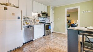 A modern kitchen with white cabinets, stainless steel appliances, and a tiled backsplash. - Walk to Lake Conroe - Condo w/ Community Perks! (Montgomery)