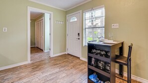 A hallway with wooden flooring, a door, and a shelf with glass jars. - Walk to Lake Conroe - Condo w/ Community Perks! (Montgomery)