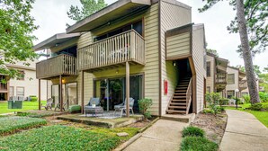 A modern multi-story building with a balcony, outdoor seating, and a well-maintained garden. - Walk to Lake Conroe - Condo w/ Community Perks! (Montgomery)