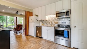 A modern kitchen with white cabinets, stainless steel appliances, and a wooden floor. - Walk to Lake Conroe - Condo w/ Community Perks! (Montgomery)