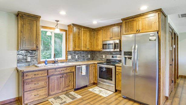 A kitchen with wooden cabinets, stainless steel appliances, and a stone backsplash. - 'elbow Lake Escape' w/ Dock in Underwood! (Underwood)