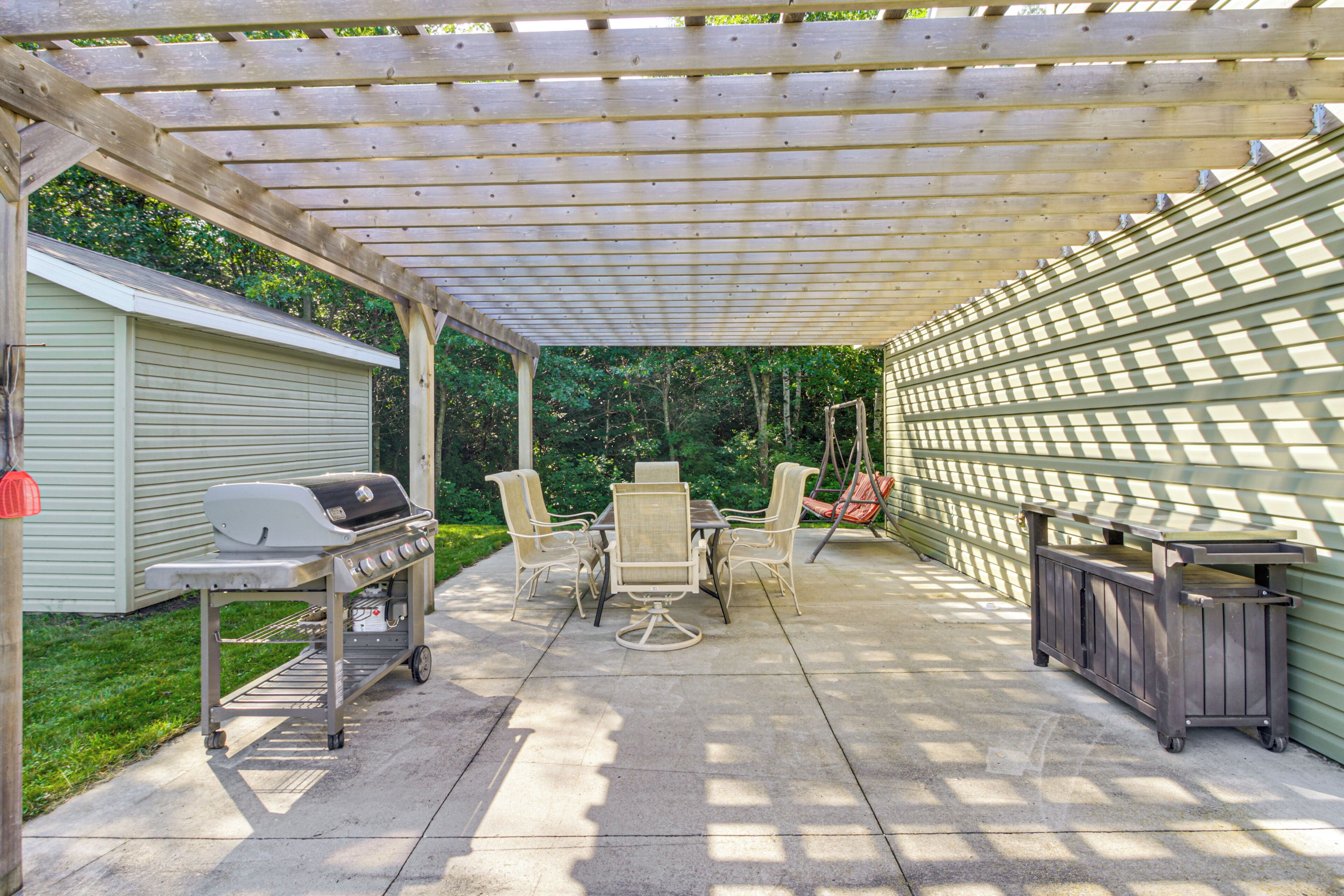 An outdoor patio with a grill, dining table, and chairs.