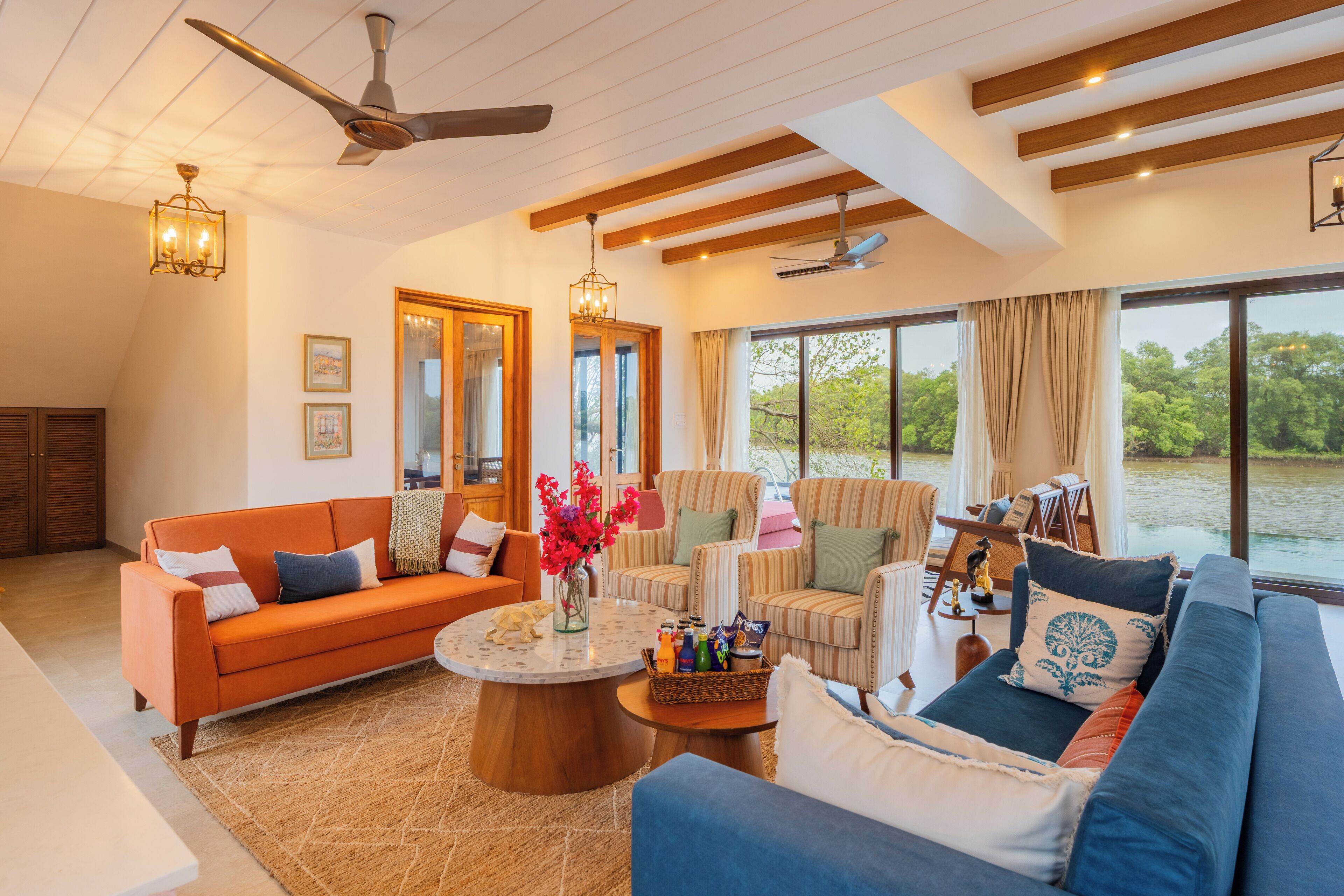 A spacious living room with a large window, a ceiling fan, and a variety of seating options including a sofa, chairs, and a coffee table with decorative items.