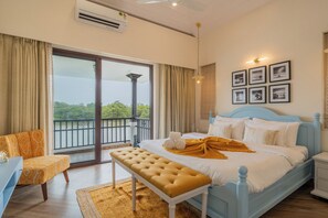 Un dormitorio con una cama grande, un banco, una silla y vistas a un balcón.
