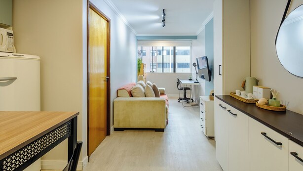 A compact living space with a kitchenette, a sofa, a dining table, and a view of the outside. - Apto 1Q 350m do PQ. Bosque do Sudoeste - SVS0219 (Sudoeste e Octogonal)