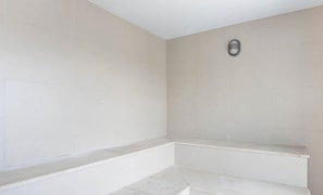 A bathroom with white tiles, a bench, and a small mirror on the wall. - Studio em cond. c/ Academia, Asa Norte SMZ407 (Brasília)