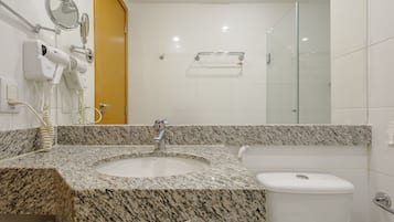 Ein Badezimmer mit Granitwaschtisch, Waschbecken, Toilette und einer Duschkabine aus Glas.