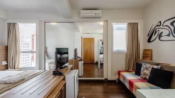 Una habitación de hotel moderna con una cama de madera, un sofá, un escritorio y vistas a la ciudad.