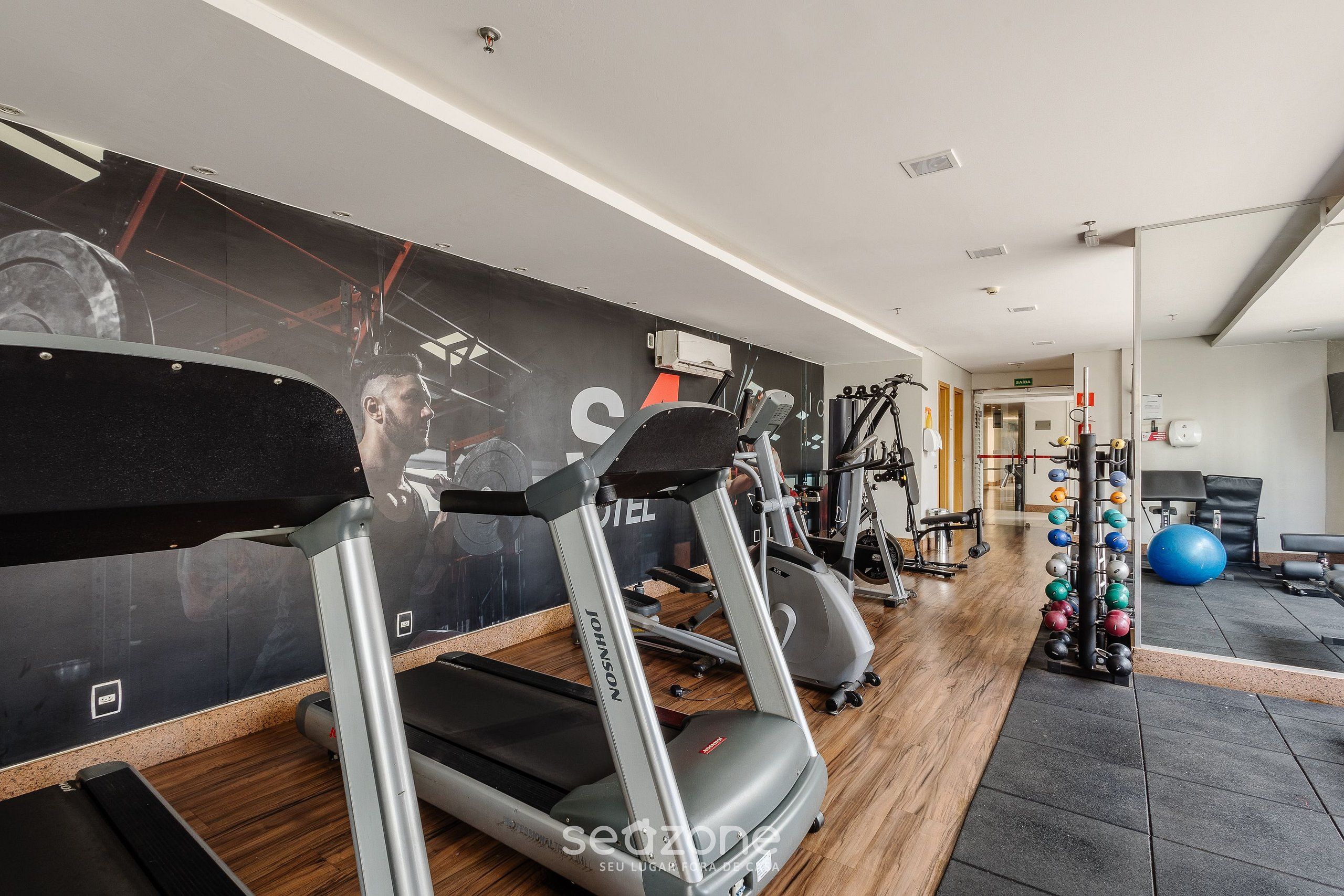 Un gimnasio con cintas de correr, máquinas de pesas y pelotas de ejercicio.