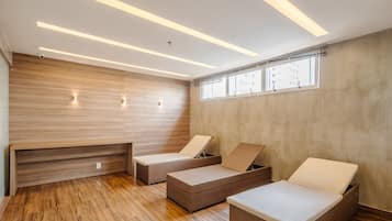 Ein moderner Wellnessraum mit Holzwandverkleidung, Holzboden und zwei Korbsessel mit Kissen.