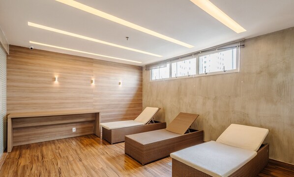 A modern spa room with wooden panel walls, a wooden floor, and two wicker lounge chairs with cushions. - Studio With Pool in Aguas Claras Sht1701 (Águas Claras)