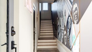 Un corridoio con una scala, una porta con serratura e un muro decorato con disegni di banconote da dollaro.