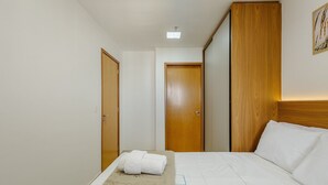 A hotel room with a bed, a wooden wardrobe, and a door. - Condomínio Bem localizado com Piscina TCR (Taguatinga)