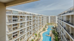 A multi-story hotel with balconies, a swimming pool, and a landscaped area. - Condomínio Bem localizado com Piscina TCR (Taguatinga)