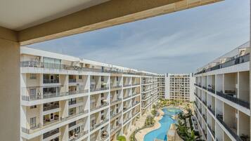 A multi-story hotel with balconies, a swimming pool, and a landscaped area.