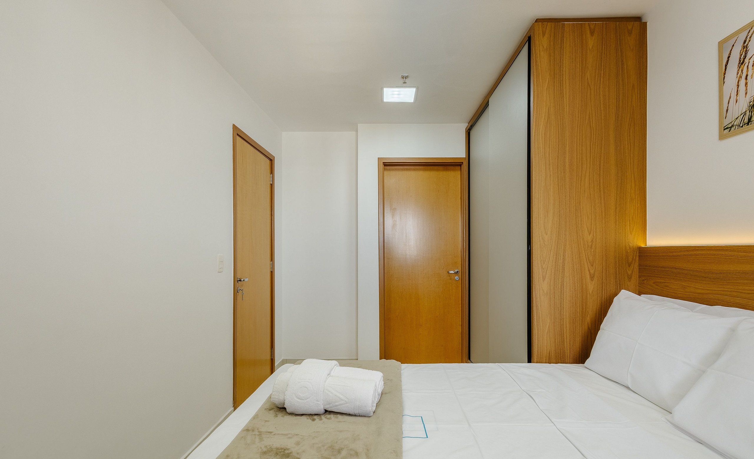 A hotel room with a bed, a wooden wardrobe, and a door.