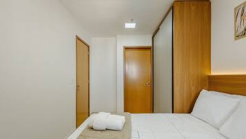 A hotel room with a bed, a wooden wardrobe, and a door.