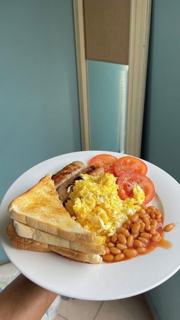 Un plato de comida para el desayuno que incluye tostadas, huevos, tomates y frijoles.