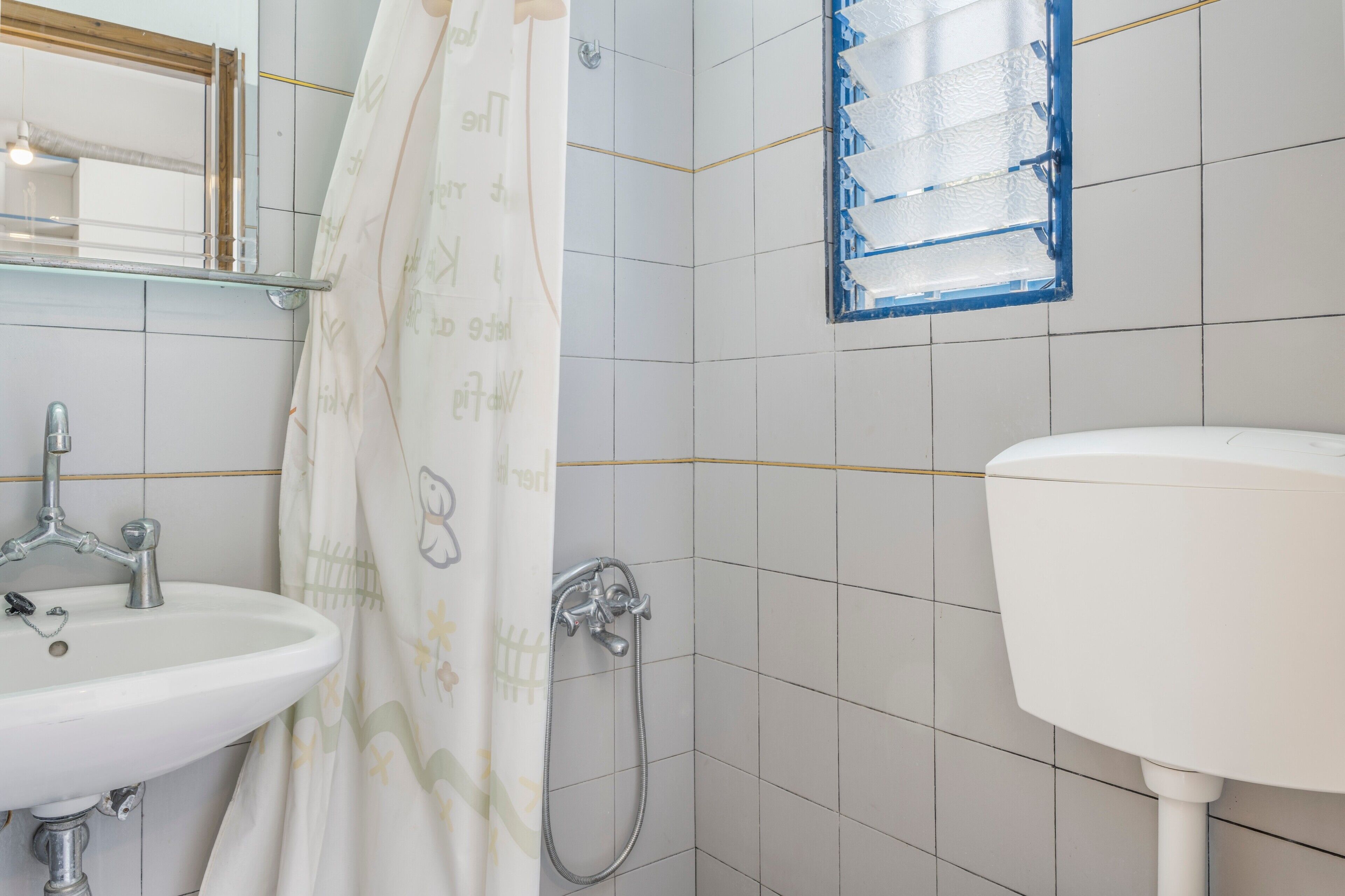 A bathroom with a white sink, a shower, and a toilet.