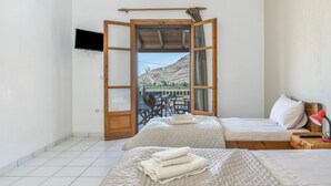 A bedroom with two beds, a TV, and a balcony with a table and chairs. - Studio Apartment '5' with Sea View, Wi-Fi and Air Conditioning (Kea)