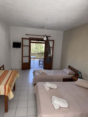 Una habitación con dos camas, una mesa, un televisor y un balcón.
