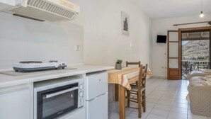 A compact kitchen with a built-in oven, a stove, and a ceiling-mounted air conditioner. - Studio Apartment '5' with Sea View, Wi-Fi and Air Conditioning (Kea)