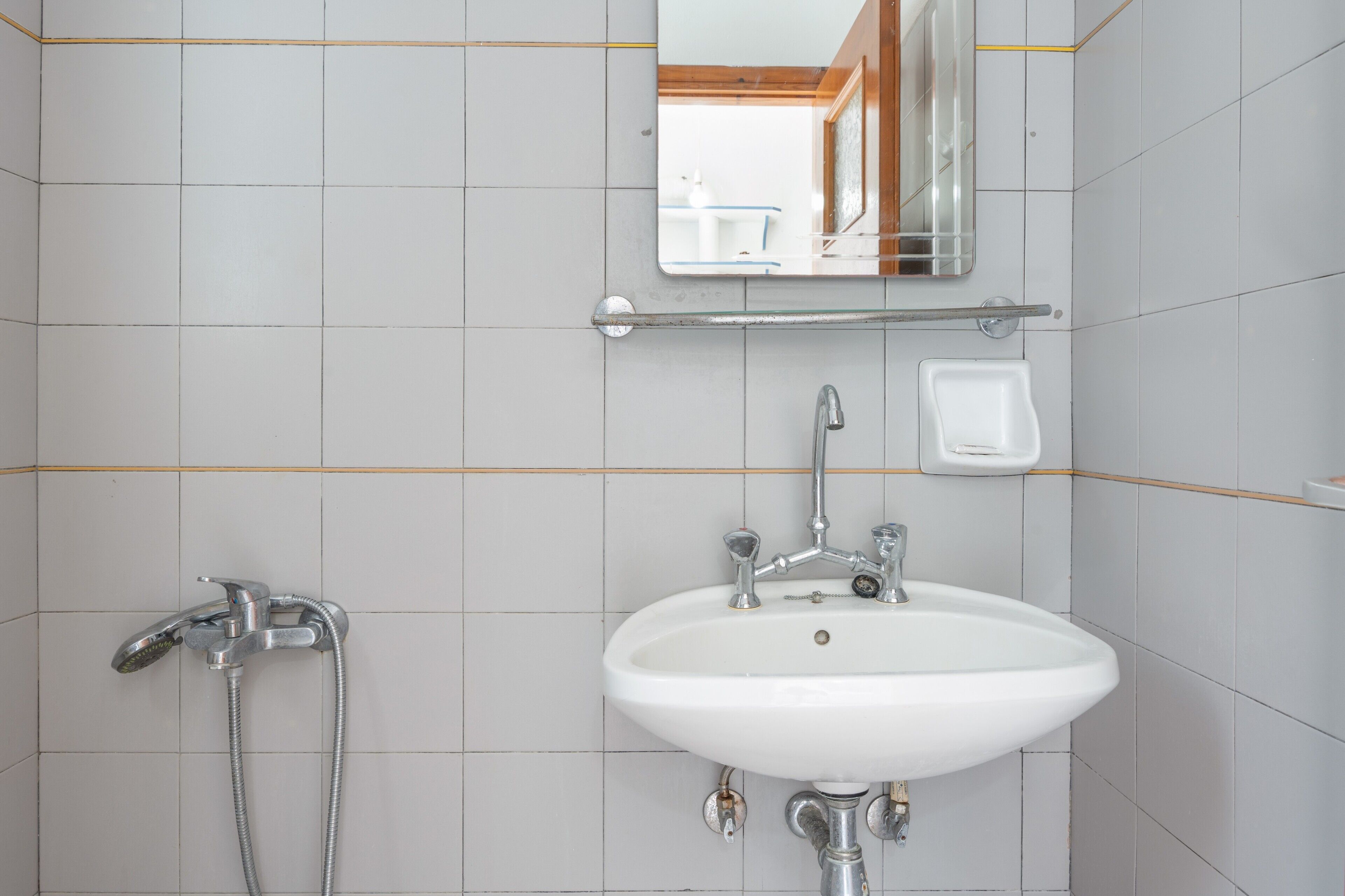 Une salle de bain avec un lavabo blanc, un miroir et une douche.