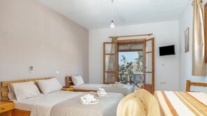 Une chambre avec deux lits, une télévision, une fenêtre donnant sur un beau paysage et un chapeau de paille posé sur l’un des lits.