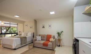 A modern bedroom with a bed, a sofa, and a small table with a plant. - Studio Near the Park in Asa Norte Sce114 (Brasília)