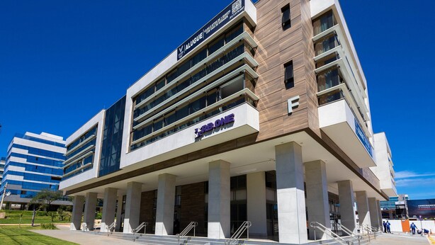 Un edificio moderno con un cartello ben visibile 'Alugue', diversi piani e il logo 'KBBONE'.